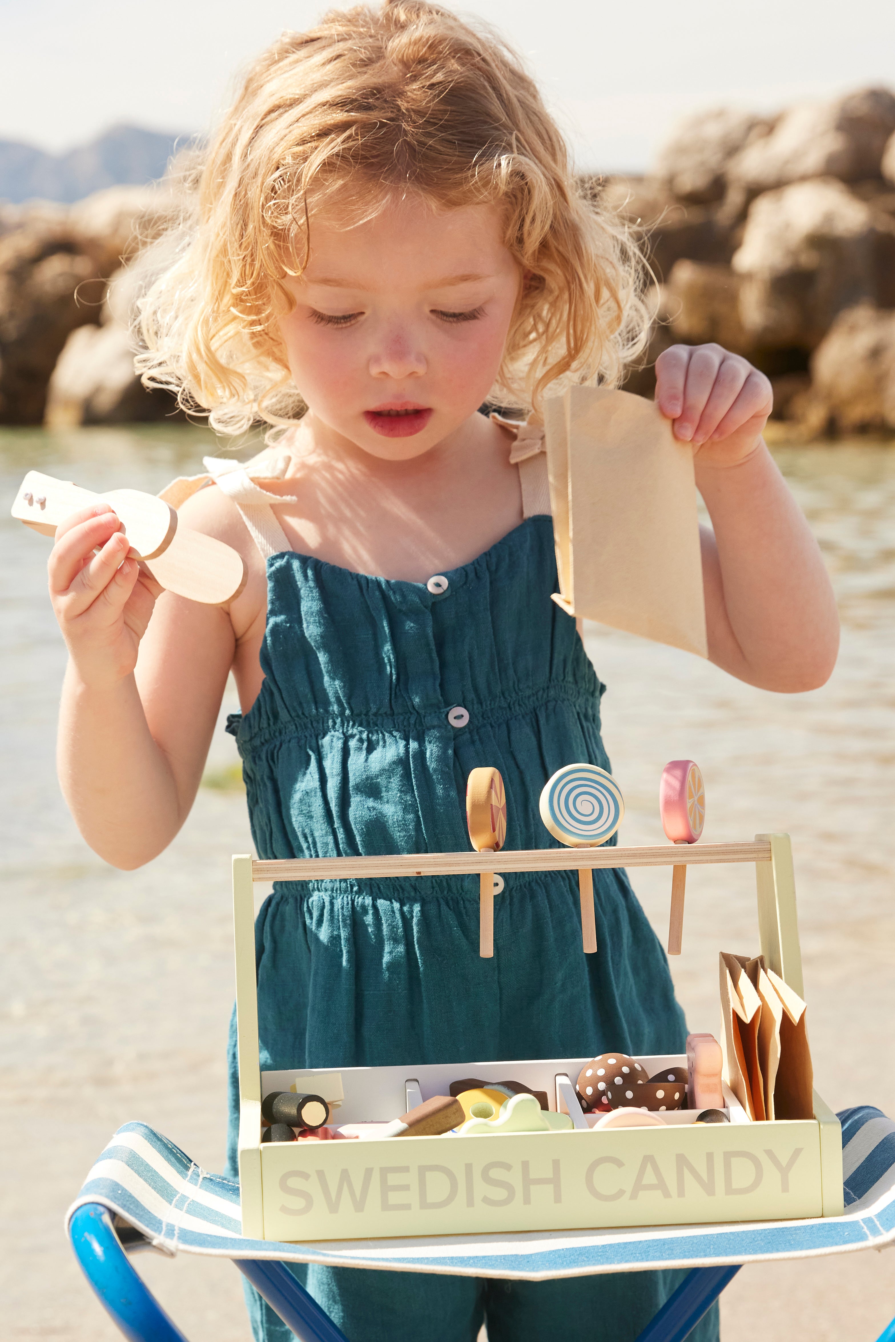 Child playing with a Kids Concept Swedish candy shop play set on a beach.
