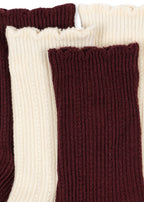 Close-up of the Konges Sløjd Bow 2-pack Pointelle Socks in Bordeaux/ Off white on a white background.