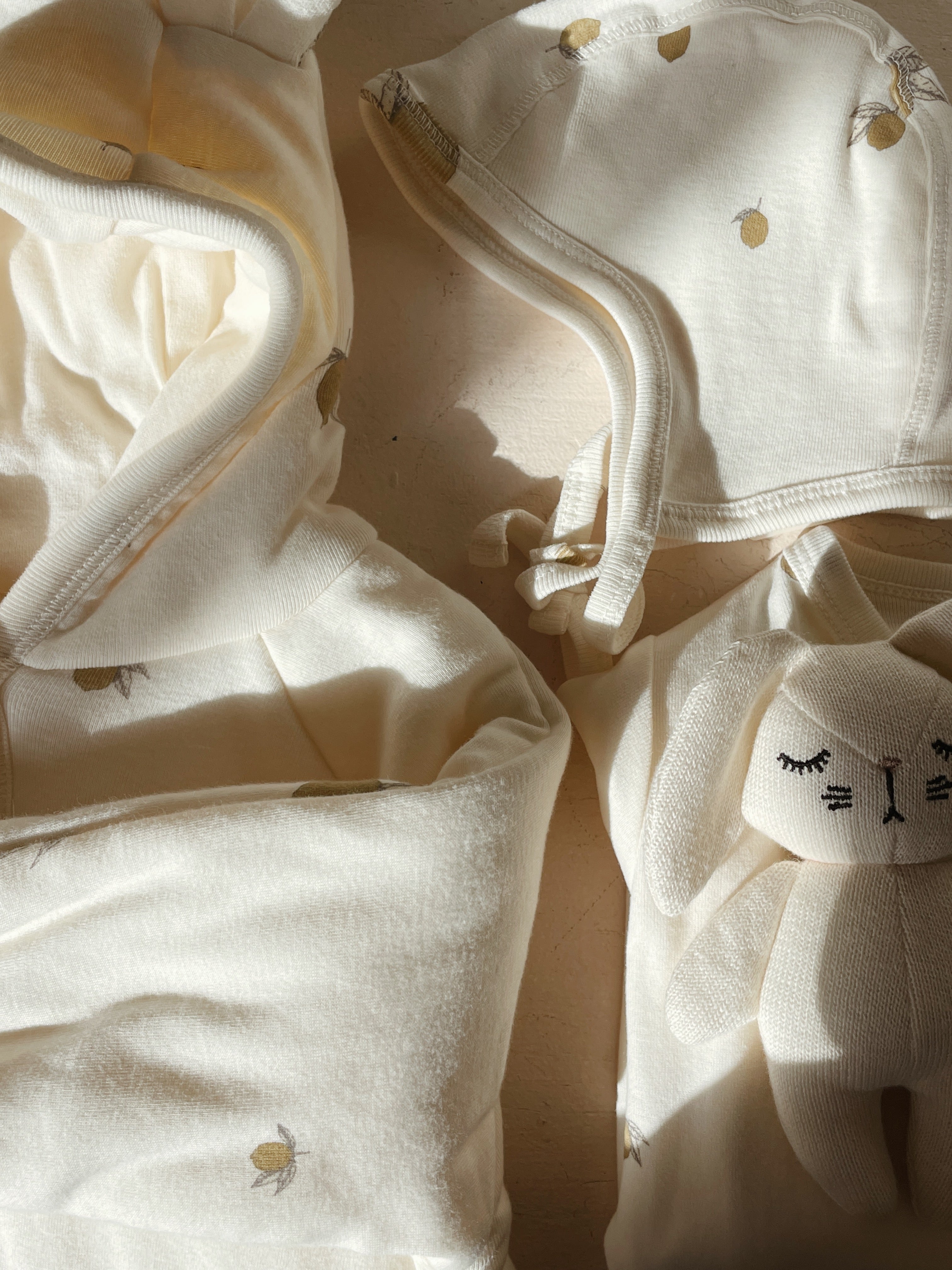 Close-up of Konges Sløjd Baby helmet in Lemon with a small plush toy (not included) on a neutral background