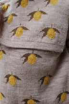 Close-up of Konges Sløjd Belou lemon knit sweater fabric and collar on white background