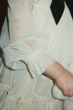 Close-up of a child wearing the Konges Sløjd Bow Dress in Parchment.