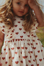 Child wearing a Konges Sløjd Cianna bow dress in Amour rouge in an outdoor setting