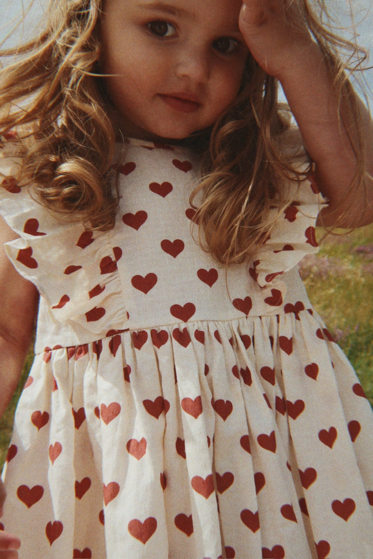 Child wearing a Konges Sløjd Cianna bow dress in Amour rouge in an outdoor setting