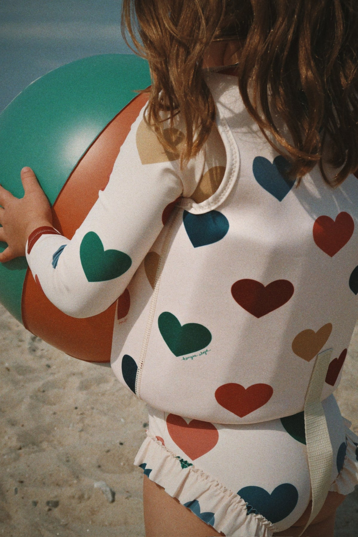 Child wearing a Konges Sløjd Ellis swim vest in bon coeur coloré while holding a colorful ball.