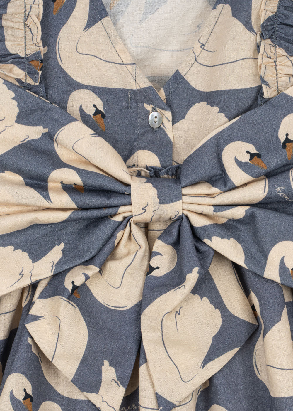 Close-up of the Konges Sløjd Evia long-sleeve bow dress in Swan print on a white background.