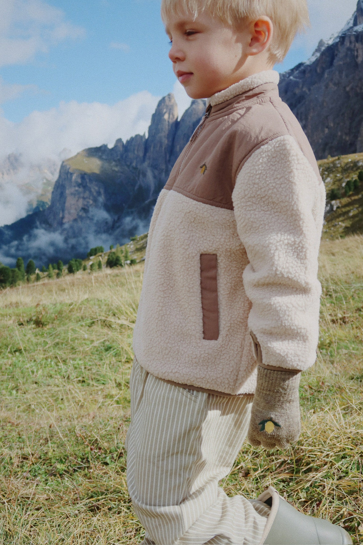 Child wearing a Konges Sløjd Flynn fleece jacket in Oxford Tan in a mountainous landscape