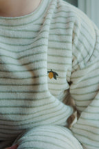 Close-up of a child wearing a Konges Sløjd Itty sweat shirt in Tea stripe