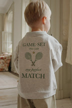 Child wearing the Konges Sløjd long-sleeve polo in off-white melange in a neutral room