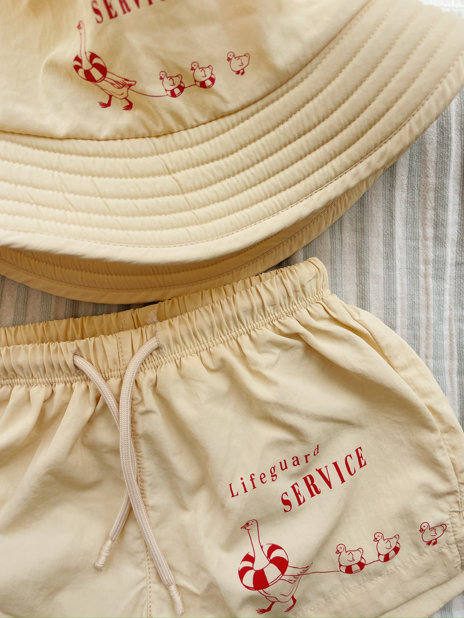 Front view of a Konges Sløjd Pomio bucket hat in banana crepe styled with the Pomio short swim shorts (not included)