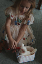Young girl in the Konges Sløjd Yvonne puff dress in Bacio playing with a toy on the floor.