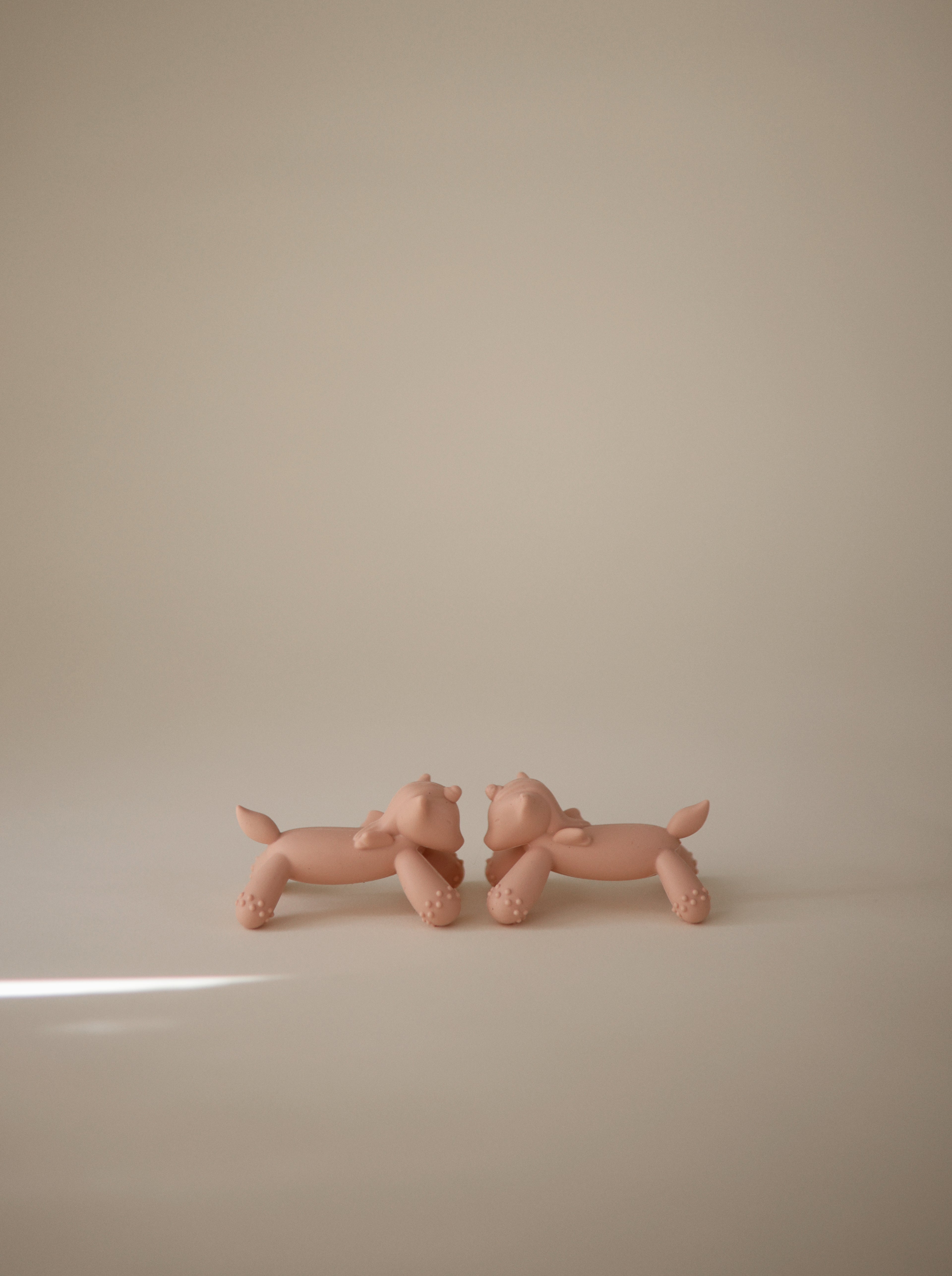 Two Mushie figurine teethers in Unicorn on a beige background