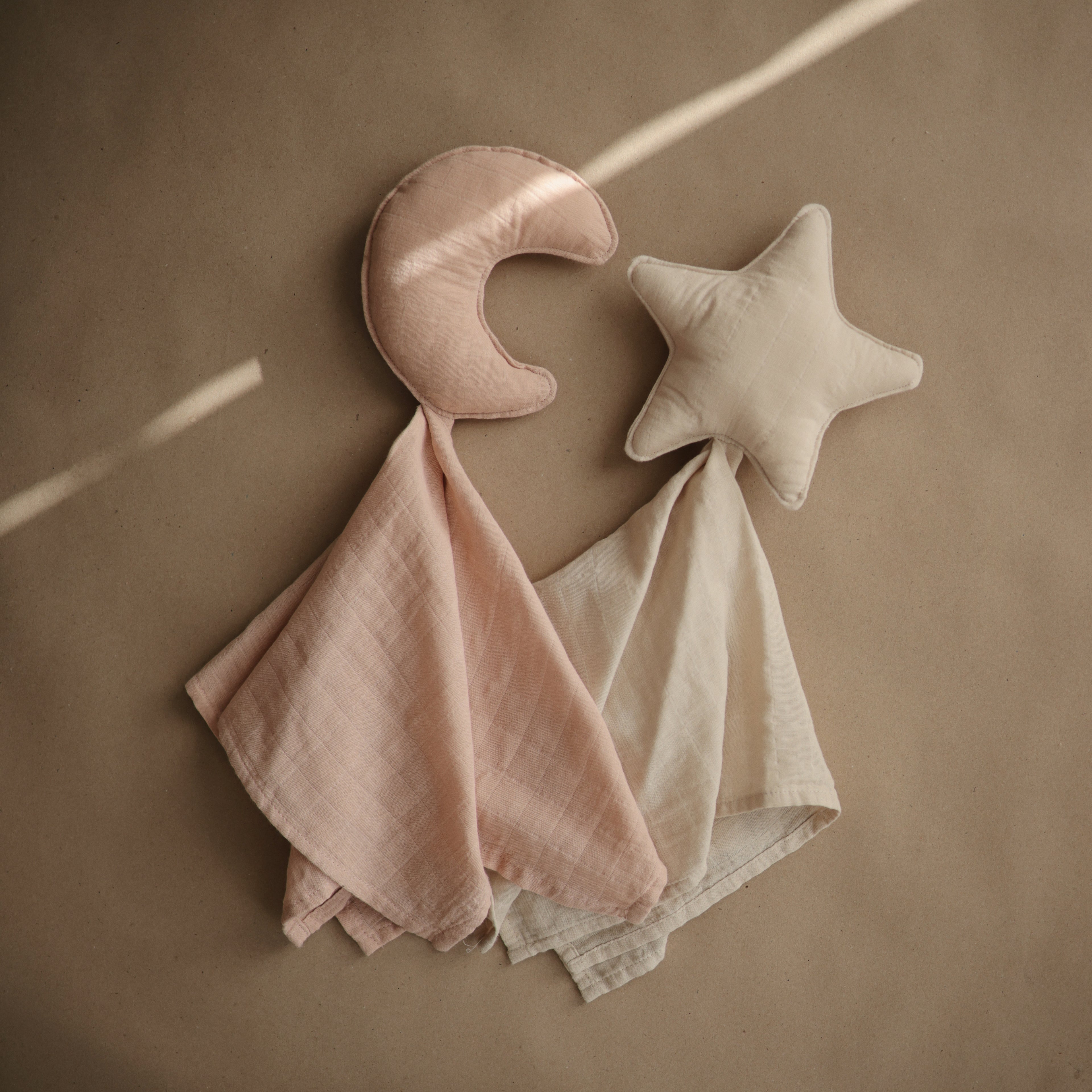 Mushie lovey blanket star in Natural styled next to a Mushie lovey blanket moon in Blush