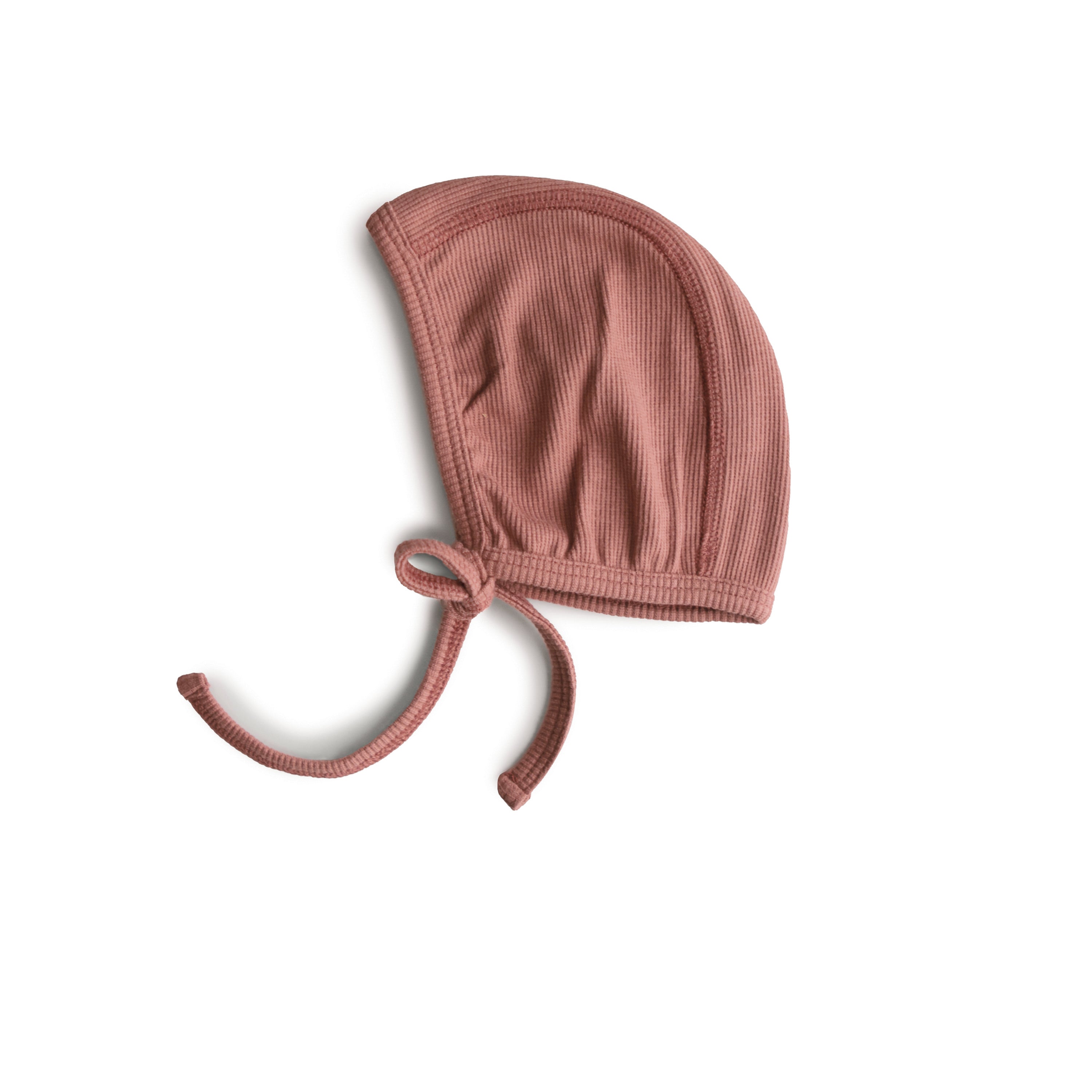 Mushie ribbed baby bonnet in Cedar on a white background
