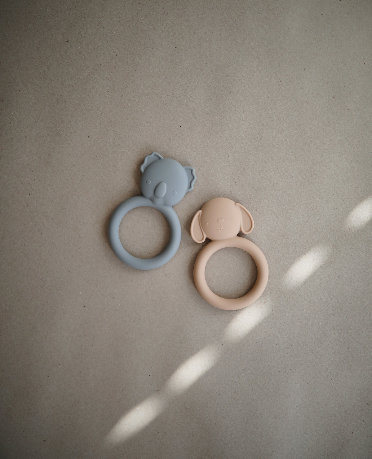 Mushie silicone teether in Dog and Koala on a beige background