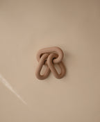 Mushie links teether in Natural on a beige background