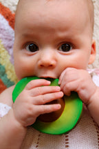 Baby holding a Oli&Carol Arnold the Avocado natural rubber teether