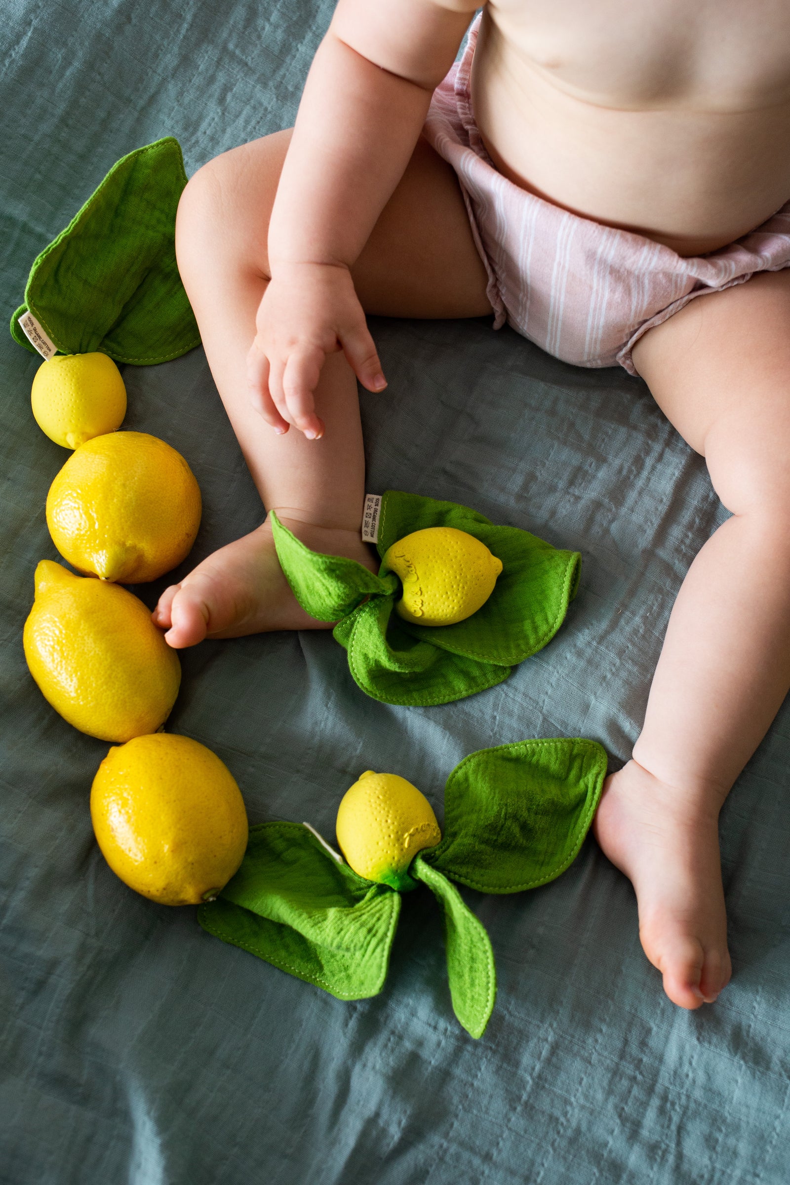 Child playing with lemons and Oli & Carol Lou the Lemon doudou teether in natural rubber