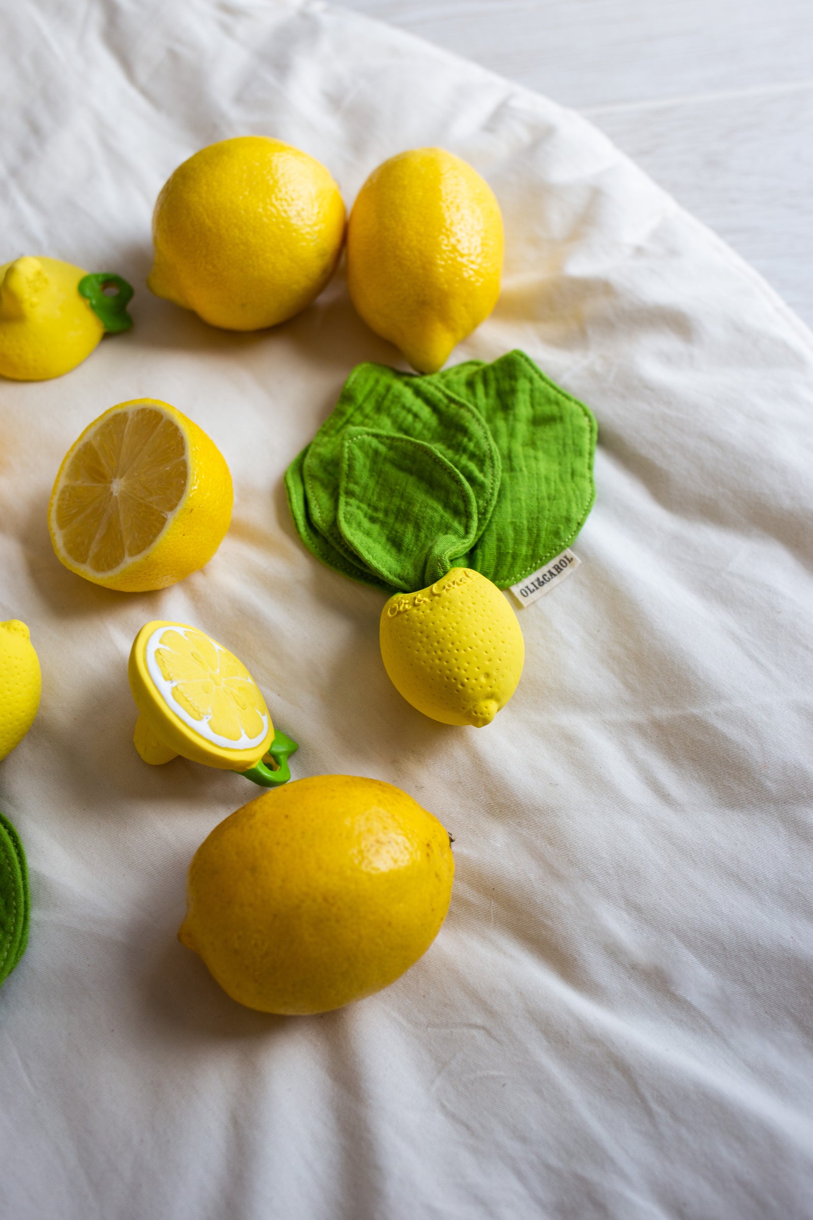 Oli & Carol Lou the Lemon doudou teether in natural rubber styled with lemons on a white-colored fabric 