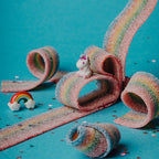 Petit Boum Magic Rainbow sensory bottle lifestyle image showing a unicorn figurine, a rainbow charm and rainbow-shaped candies arranged nearby
