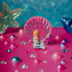 Petit Boum Sea sparkle sensory bottle lifestyle image showing a mermaid with a shell on a pink surface with decorative elements