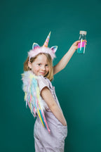 Lifestyle image of a girl wearing a unicorn costume and holding a Petit Boum Unicorn sensory bottle