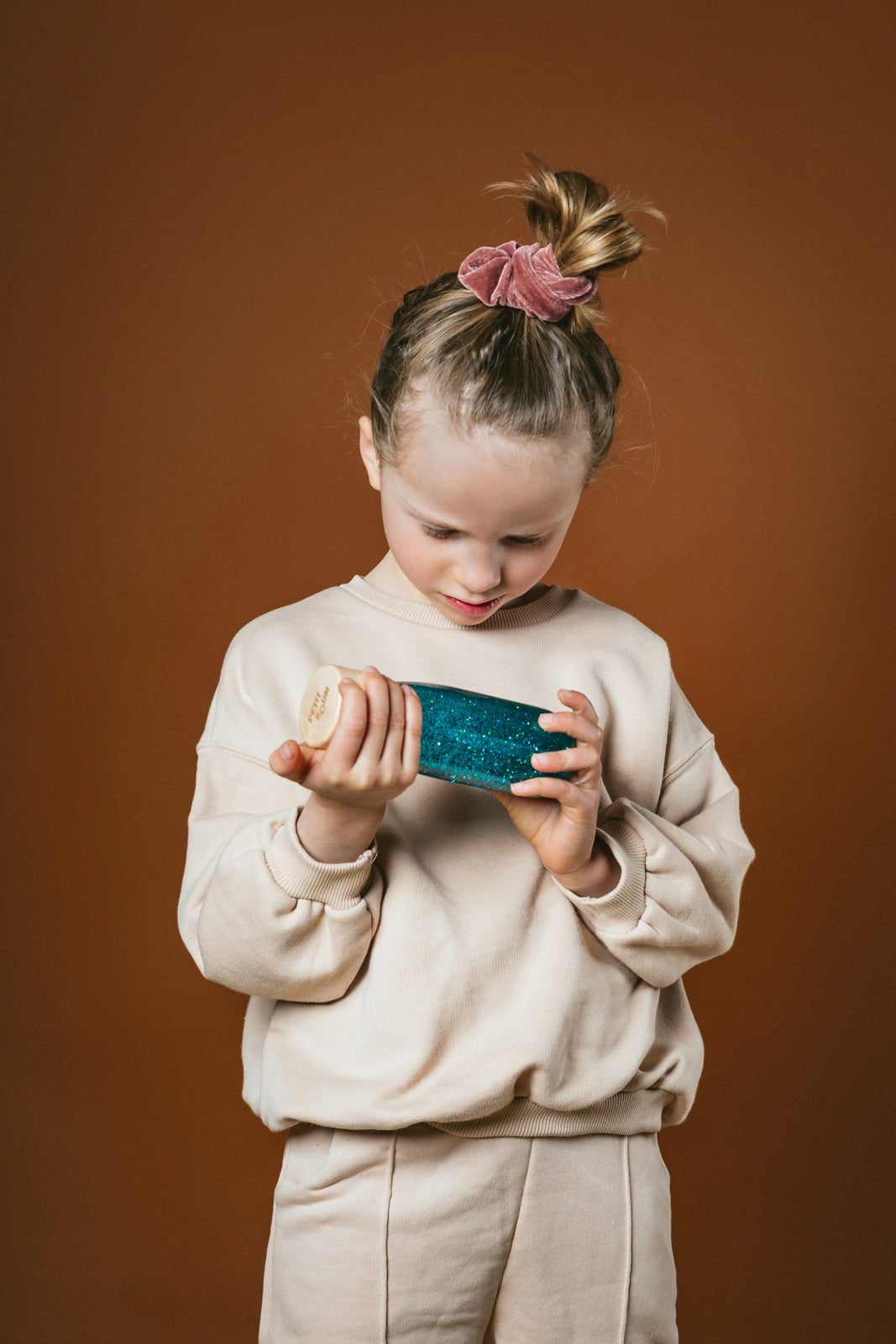 Lifestyle image of a girl holding and looking at a Petit Boum Turquoise sensory bottle
