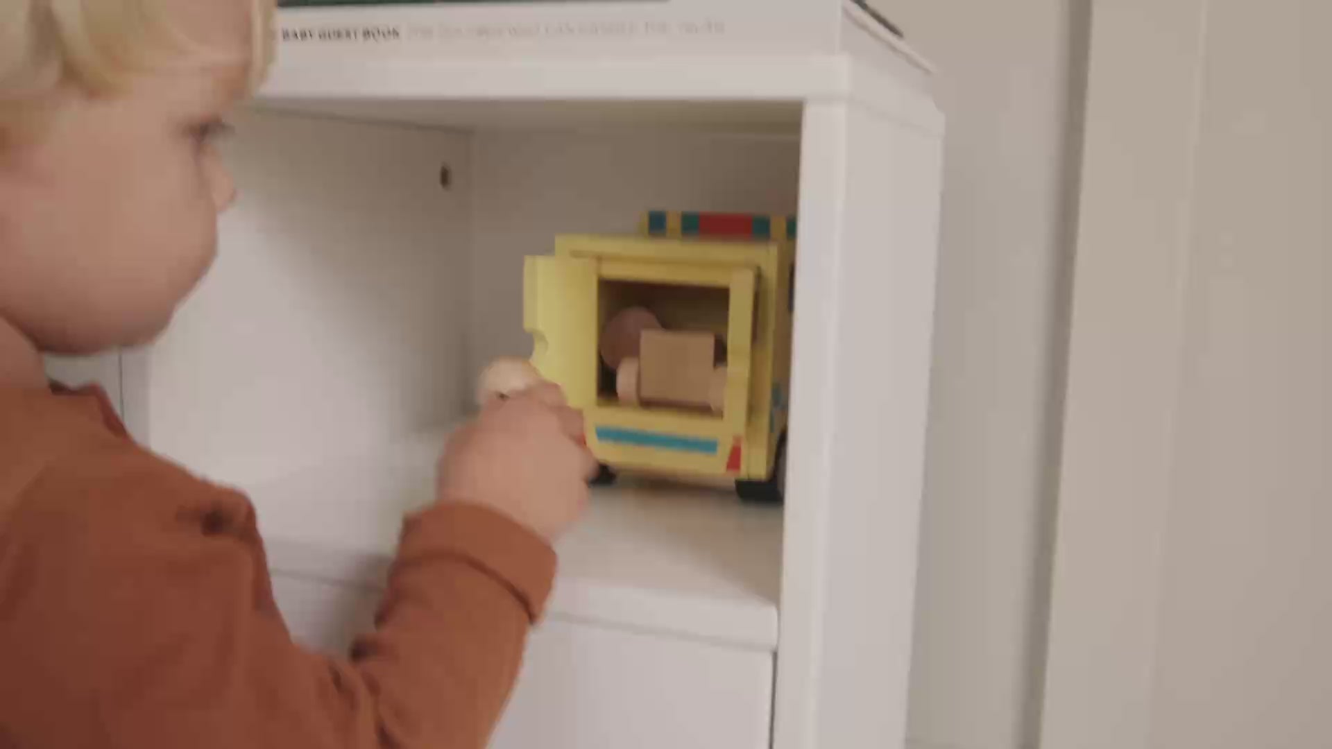 Child playing with a Kids Concept wooden toy ambulance in a neutral styled living room